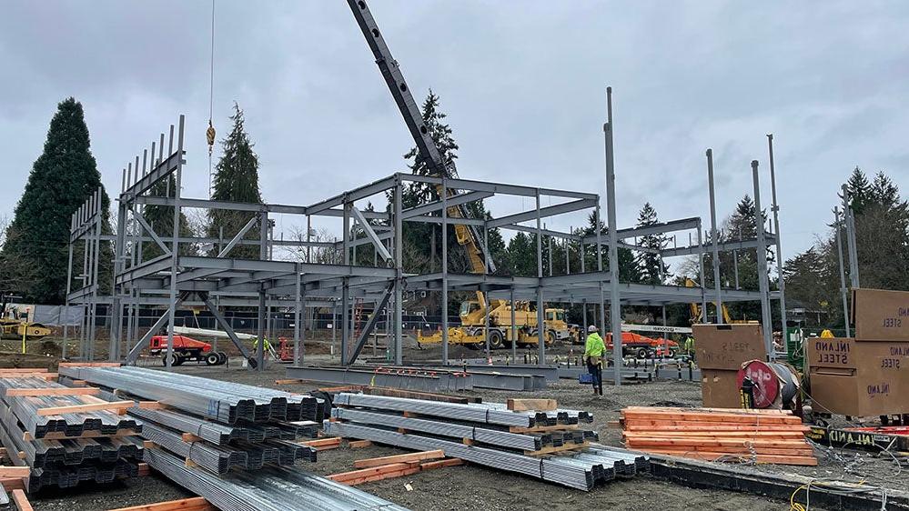 a crane is installing steel framing for a large building